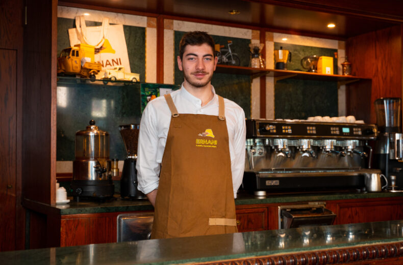 Foto a Davide, banconista della Torrefazione Ernani a Milano, in posa con la divisa dietro al bancone della caffetteria.