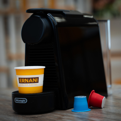 Foto della macchina a capsule della Delonghi con tazza e capsule Caffè Ernani