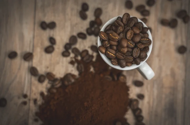 Foto dei chicchi e del caffè macinato Ernani a tostatura Media, su sfondo legno